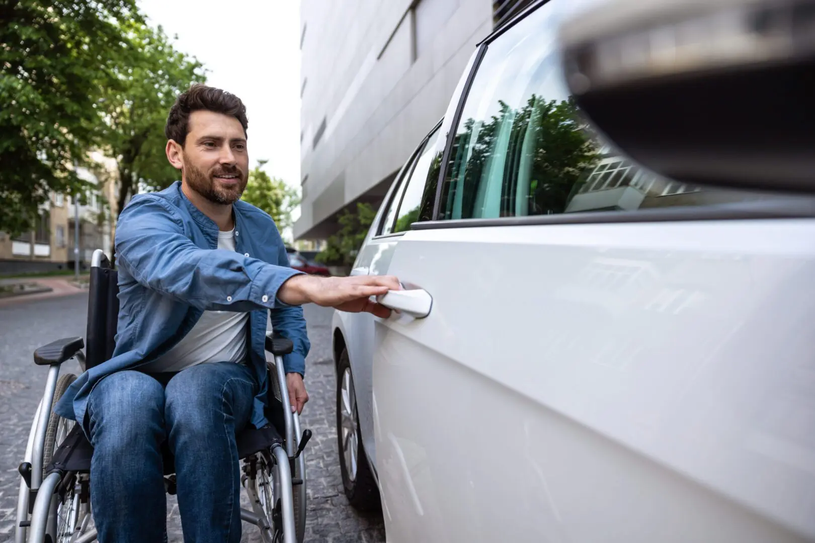 Man in wheelchair opening car door with a smile.