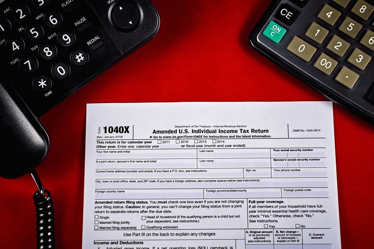 1040X tax form with phone and calculator.