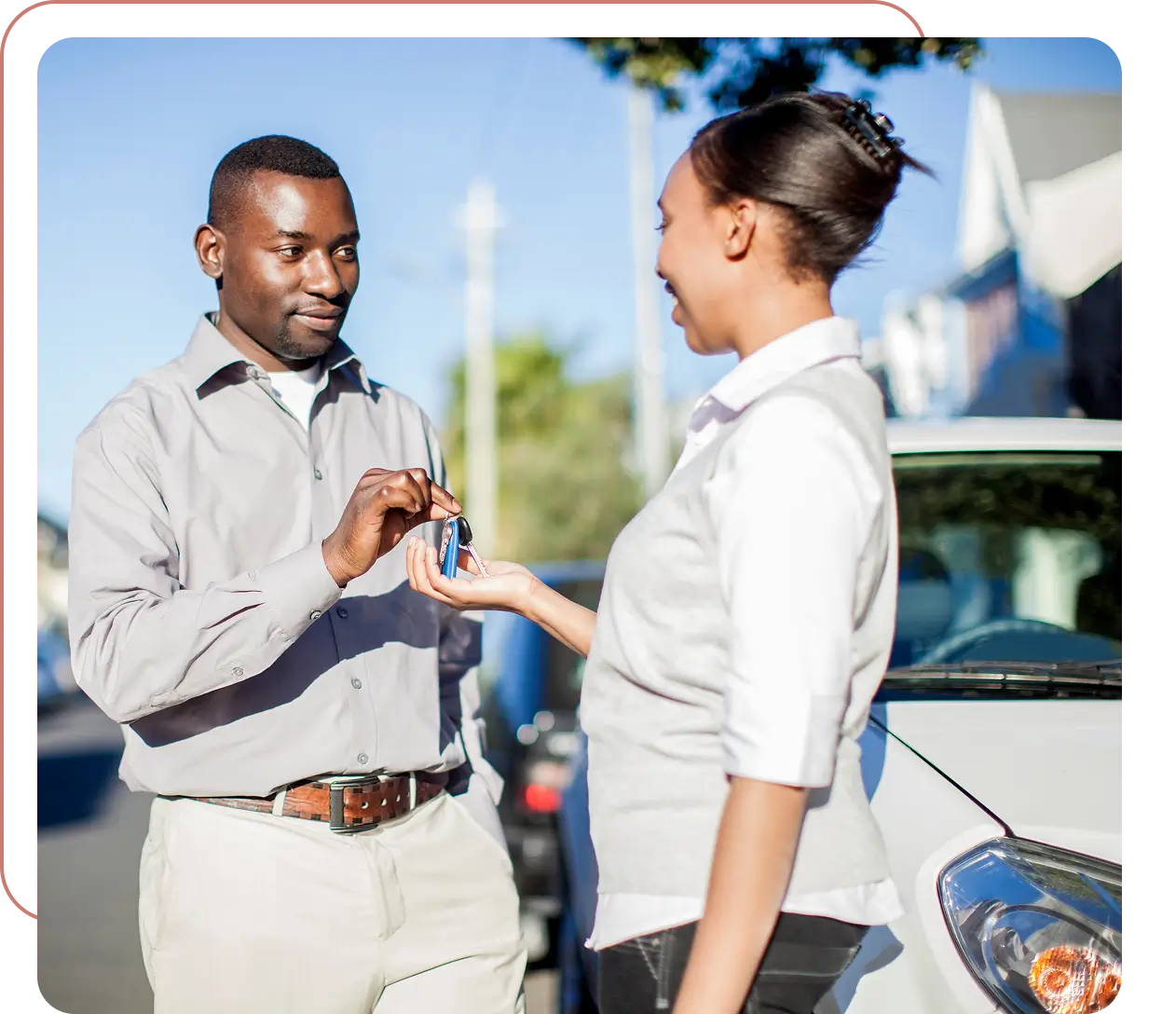 Man handing car keys to woman outside.